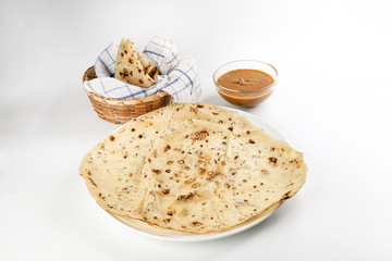 Paper thin rumali roit wheat chapati bread on white plate best served with dal tadka makhana