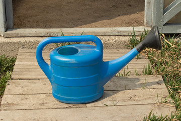 watering can stands in the garden on the blackboard