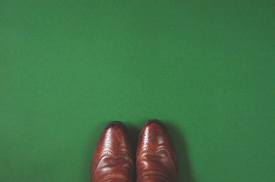 Men's brown boots on a green background.