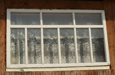 the window is wooden. window in a wooden building
