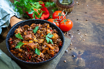 Indian cuisine dish. Traditional indian spicy green lentils with meat, spices, herbs in a cast-iron frying pan on a wooden table. Copy space.