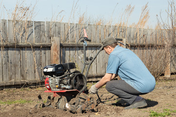 a man establishes a walk-behind tractor in a garden