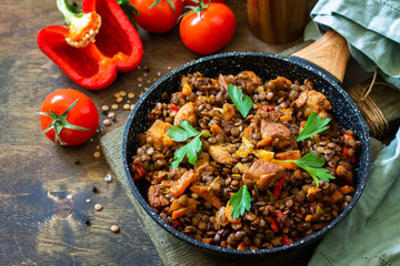 Indian cuisine dish. Traditional indian spicy green lentils with meat, spices, herbs in a cast-iron frying pan on a wooden table. Copy space.