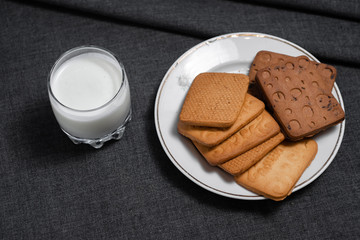 Cookies on a white plate and a glass of milk. Milk products. Photo of food on a dark background.