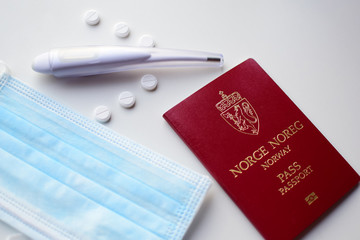 On a white background - a Norwegian passport, medical mask, thermometer and pills, airplane. Concept: travel in an epidemic, pandemic, coronavirus.