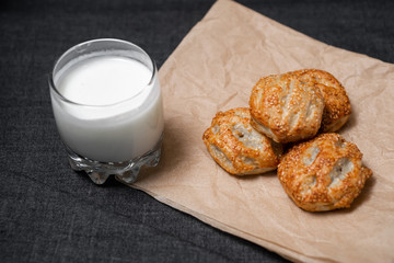 Buns from the Kraft oven, food paper and dairy products, a glass of milk.
Photo on a dark background.