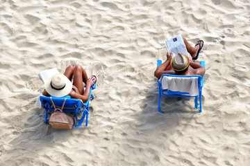 Senior couple relaxing on sand beach.  Top view horizontal. Happy retirement concept.