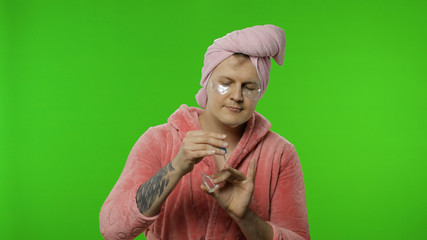 Portrait of transsexual man in bathrobe spraying perfume on neck and wrist