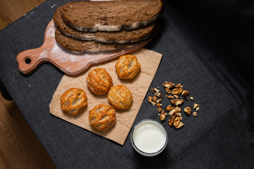 Baking, rolls, bread and milk on a dark background. Kraft, food paper and wooden board