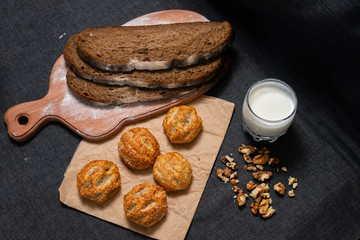 Baking, rolls, bread and milk on a dark background. Kraft, food paper and wooden board