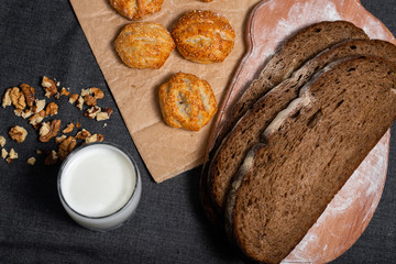 Baking, rolls, bread and milk on a dark background. Kraft, food paper and wooden board