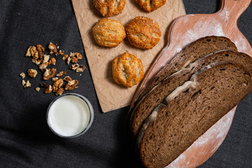 Baking, rolls, bread and milk on a dark background. Kraft, food paper and wooden board