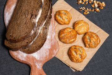 Baking, rolls, bread and milk on a dark background. Kraft, food paper and wooden board