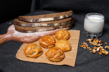 Baking, rolls, bread and milk on a dark background. Kraft, food paper and wooden board