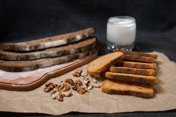 Baking, dark bread, cookies and rolls on a dark background.
Kraft paper. Milk in a transparent glass.