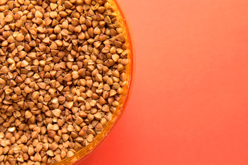 uncooked buckwheat in a container on a red background