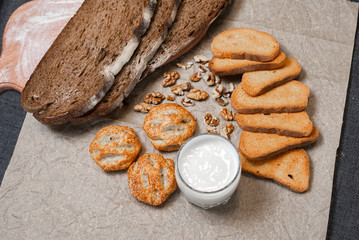 Baking, dark bread, cookies and rolls on a dark background.
Kraft paper. Milk in a transparent glass.