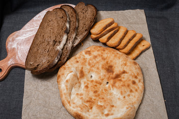 Baking, dark bread, cookies and rolls on a dark background.
Kraft paper. Milk in a transparent glass.