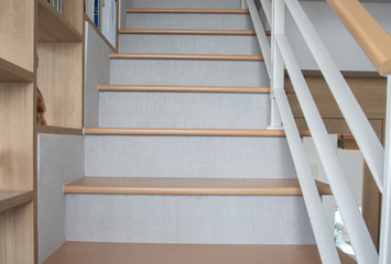 The front view of the grey wooden stairway in a modern style house in the perspective  view seeing the second floor and the railing for the family that live together for relaxation and comfort.