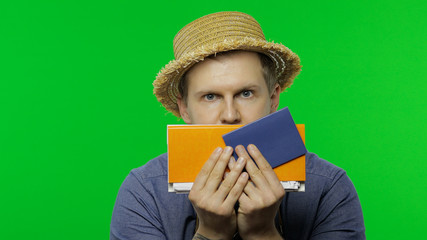 Portrait of man tourist hides behind passport and tickets and looks out