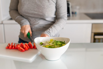 woman chopping tomatoes on kitchen. Salad preparation. Healthy lifestyle and nutrition concept.