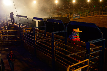 Rodeo workers from Brazil. The clown waits in the gutter before his moment to enter the rodeo arena.