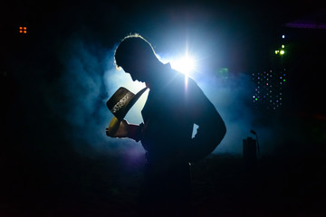 Rodeo workers from Brazil. Cowboy with hat in silhouette against bright lights.