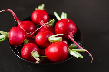 Fresh raw red radish in plate on the black wooden background