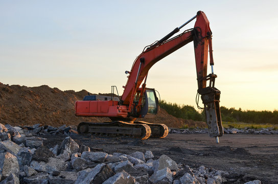 Hydraulic Breaker Hammer For The Destruction Of Concrete And Hard Rock At The Construction Site. Excavator On Sunset Background. Jackhammer Using Without Blasting Method. Hard Rock Demolition