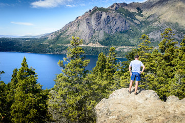 People in a mountain landscape in sunny day. Green pines and lake under the mountain in Bariloche.