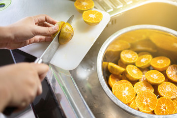 Woman cutting oranges for squeezing and making orange juice.