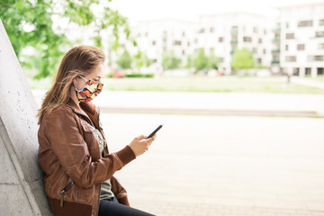 Fototapeta premium Frau mit Maske und Handy im Park