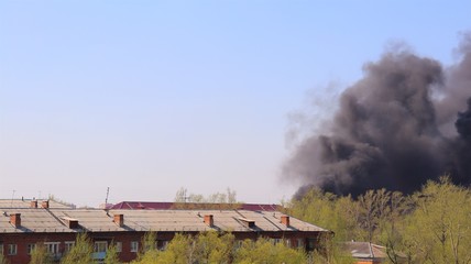 Fototapeta na wymiar Big fire in house. Black smoke in sky. City landscape.