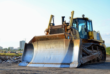 Bulldozer at construction site. Heavy equipment for digging, demolition, construction and ground works. Dozer for earth-moving, land clearing, grading, utility trenching and foundation digging