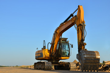 Obraz premium Excavator digs the ground for the foundation and construction of a new building. Road repair, asphalt replacement, renovating a section of a highway, laying or replacement of underground sewer pipes