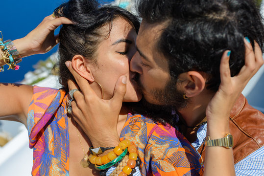 A man and a woman kiss against the backdrop of Skaros Rock on Santorini Island. The village of Imerovigli..He is an ethnic gypsy. She is an Israeli.
