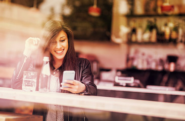 Nice girl sitting in a bar with her cell phone.