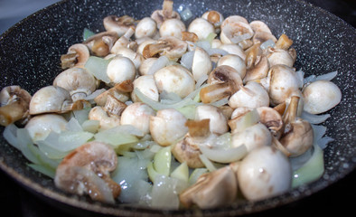 Mushrooms with onions in a frying pan. Preparing lunch and dinner.