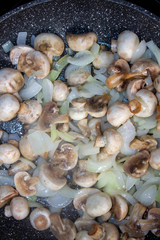 Mushrooms with onions in a frying pan. Preparing lunch and dinner.