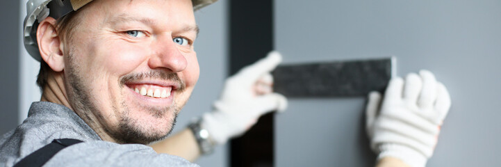 Obraz premium Builder in helmet applies metal detail to wall