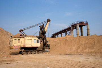 Huge mining excavator in the sand open-pit. Biggest digger working in quarry. Largest tracked machine with electric shovel. Heavy duty electric-powered mining equipment