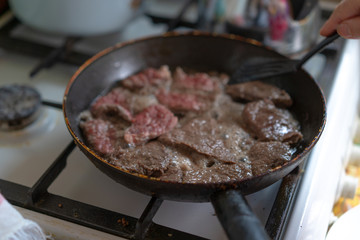 Pieces of meat are fried in a pan
