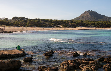 Einsame Person sitzt an der Küste mit Blick aufs Meer in Spanien