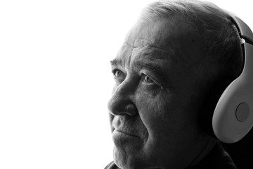 Portrait of old man in headphones listening music. White background. Free space for text. Black and white.