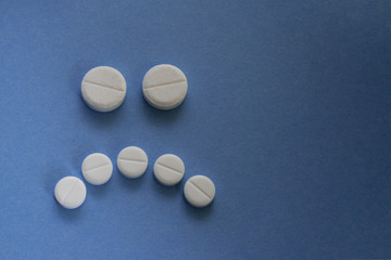 concept of bad medicine. sad face made up of pills on blue backgroud