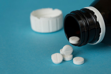 bottle with white pills on blue background with copy space