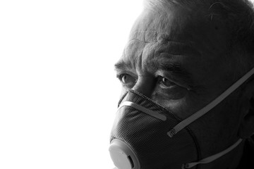 Old man in protective respirator. Male wearing medical mask. Free space for text. Coronavirus 2019-nCov. Black and white.