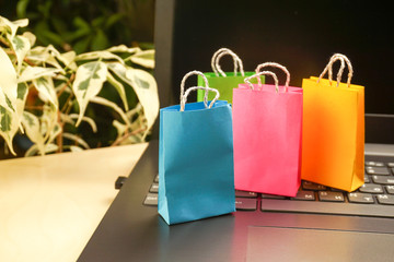 online shopping concept. little colorful shopping bags stand on laptop. copy space