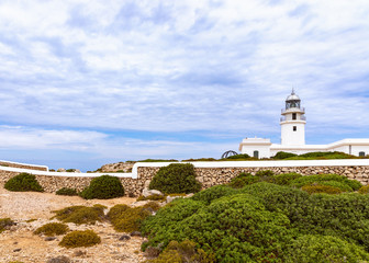 Fototapeta na wymiar Beautiful view of the lighthouse (Faro de Cavalleria) and the cloudy sky above it. Menorca, Balearic islands, Spain