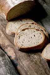 Sliced whole grain artisan rye-wheat organic bread over old wooden background. Close up